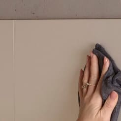 Hand mit grauem Mikrofasertuch auf einer matten Küchenfront